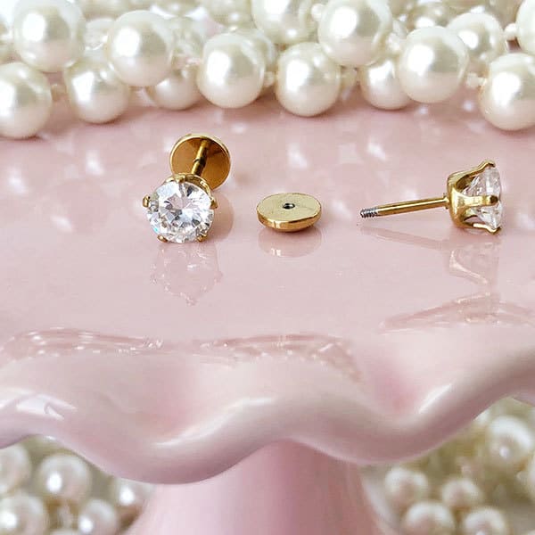 6.0 mm Crystal Gold Prong on pink with pearls in background.