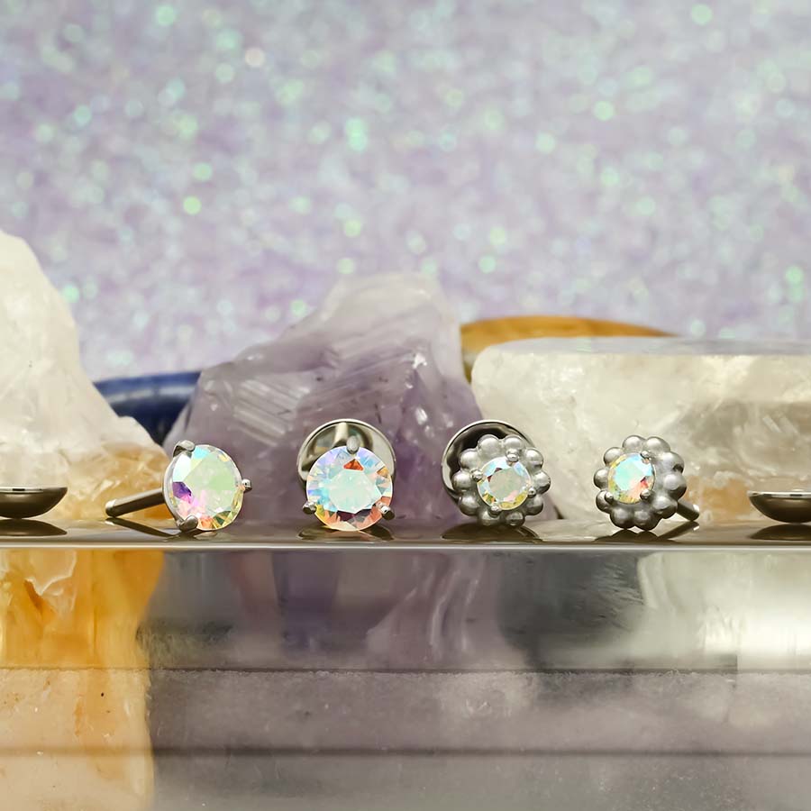Two pairs of Aurora Boralis earrings on a metallic surface with a glittery purple background.