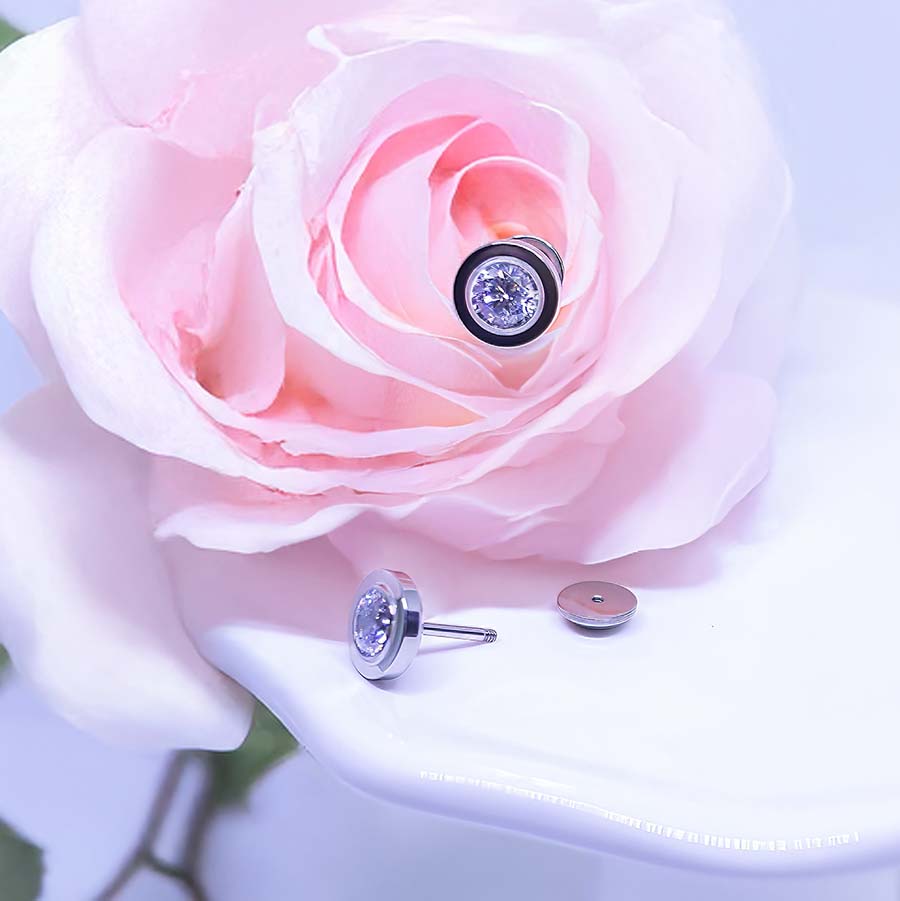Crystal Bezel Titanium ComfyEarrings with clear CZ gems on a pink rose.