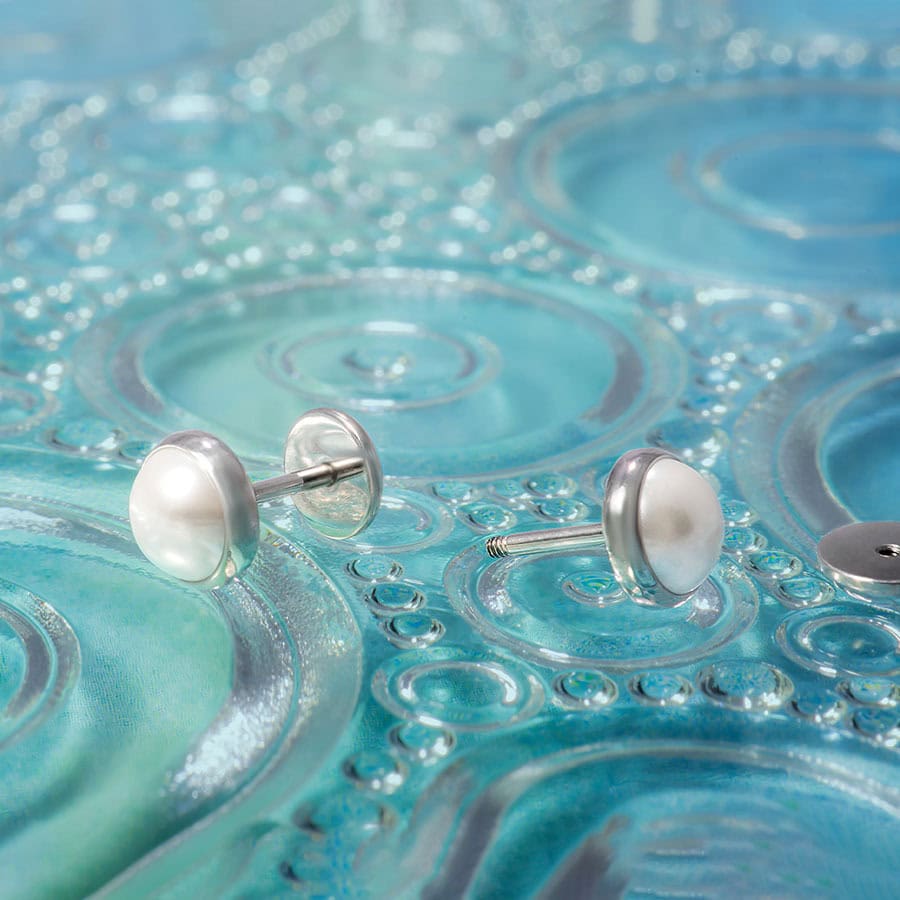 Half Pearl ComfyEarrings on a blue pattern glass plate