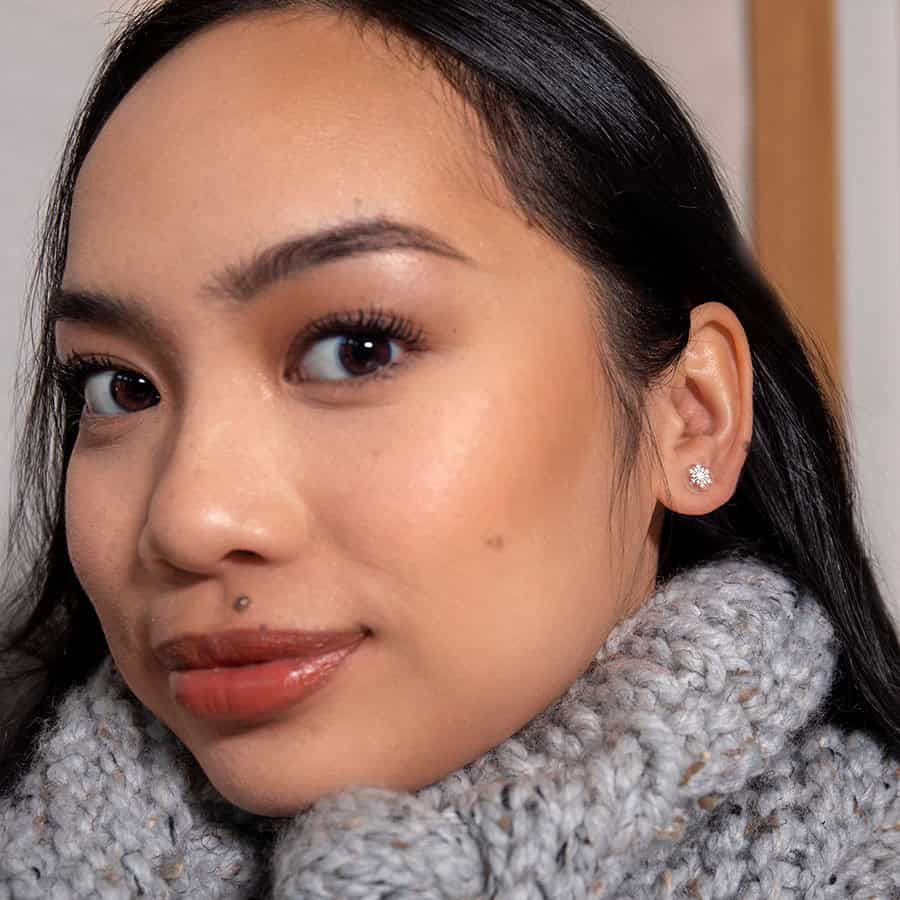 Snowflake ComfyEarrings worn in a model's ear wearing a knit scarf.
