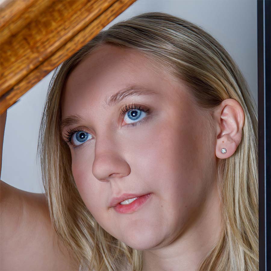 Close-up of a woman with blonde hair and blue eyes, wearing earrings.