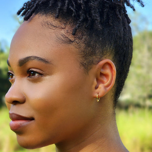Woman with styled hair outdoors. Modeling a gold hoop earring.