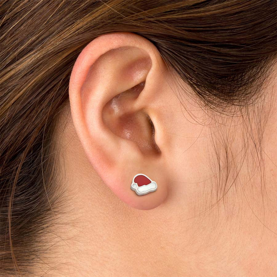 A close-up of a person's ear wearing a small stud earring shaped like a Santa hat.