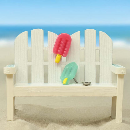 Beach scene with a wooden bench, popsicles, and a picket fence. Featuring homemade popsicle DIY ComfyEarrings.