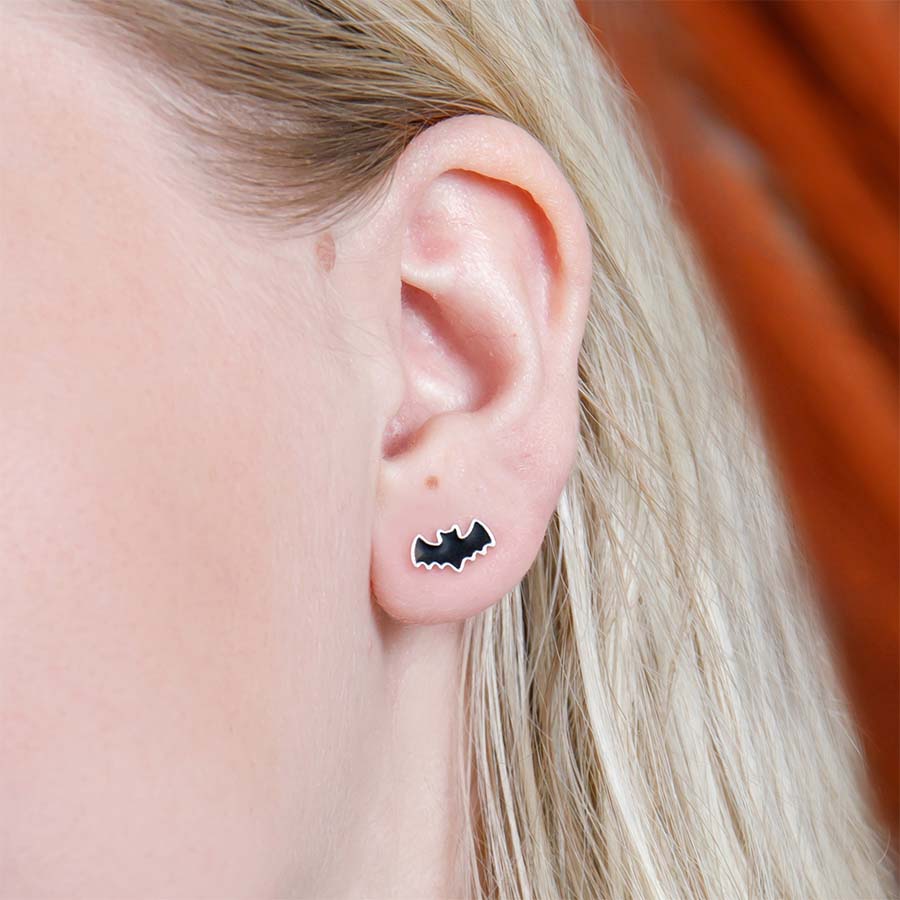Person wearing a bat-shaped earring with a blurred background