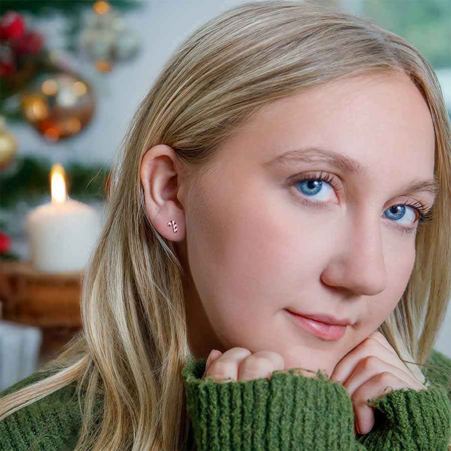 Woman wearing candy cane earrings with a blurred festive background