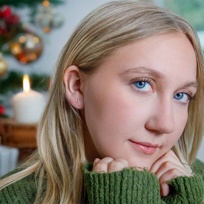 Woman wearing candy cane earrings with a blurred festive background