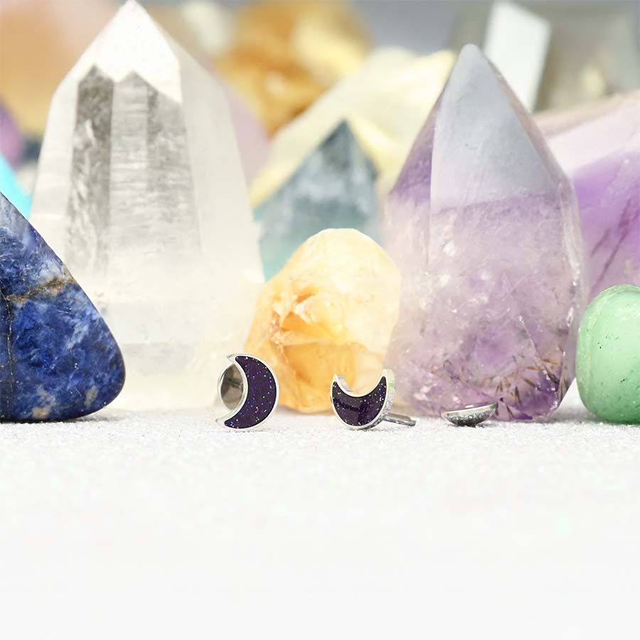 Crescent moon earrings on a background of colorful crystals