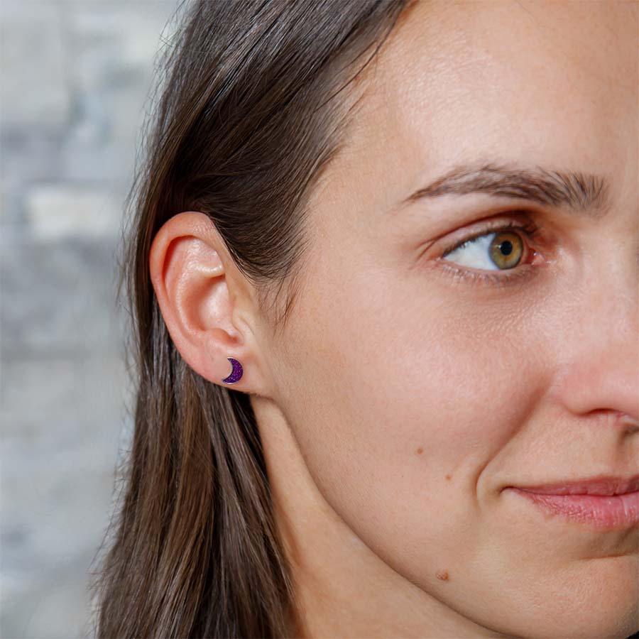 Close-up of a woman wearing crescent moon earrings with a blurred background