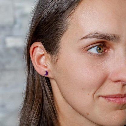 Close-up of a woman wearing crescent moon earrings with a blurred background