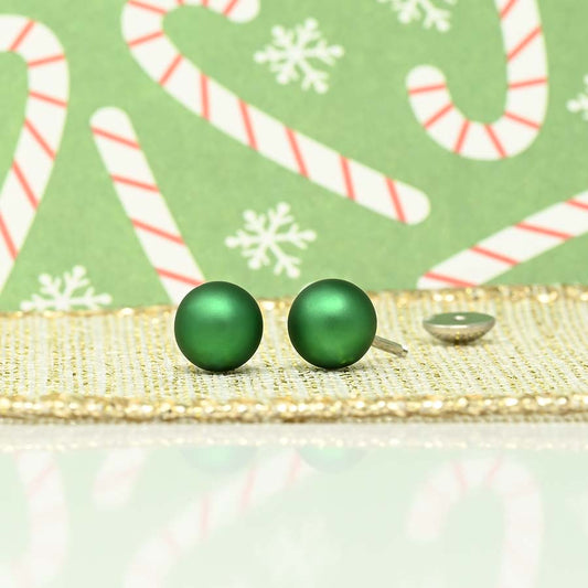 Green round pearl earrings on a decorative background with candy canes and snowflakes.