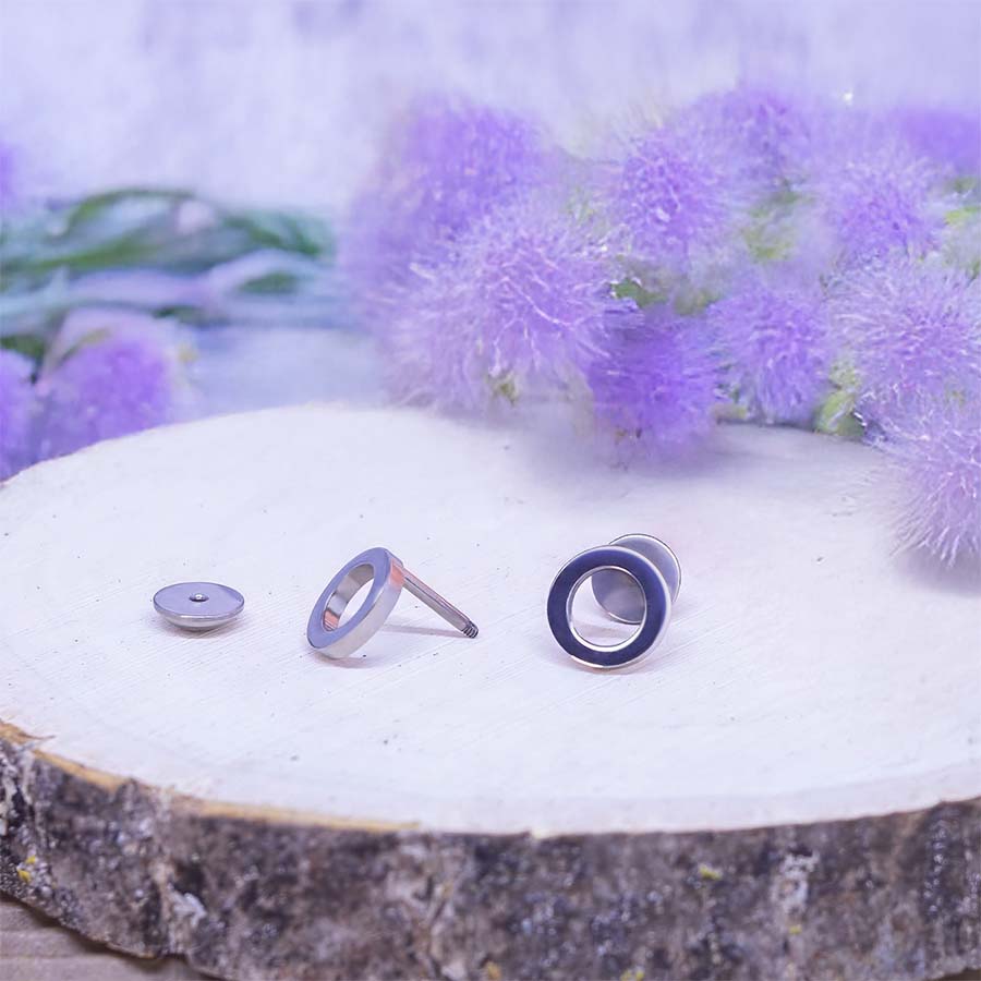 Open Circle Titanium ComfyEarrings on a wooden surface with purple flowers in the background