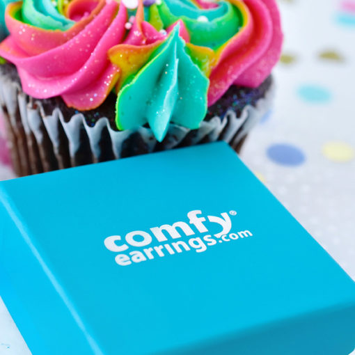 Blue ComfyEarrrings box in front of a colorful cupcake.