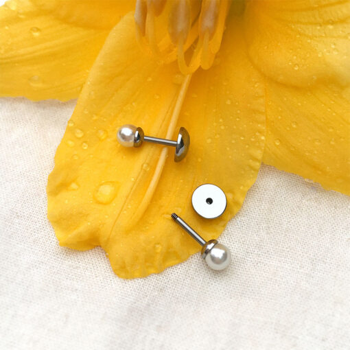 Mini Pearl ComfyEarrings sitting on yellow flower petals with dew drops.