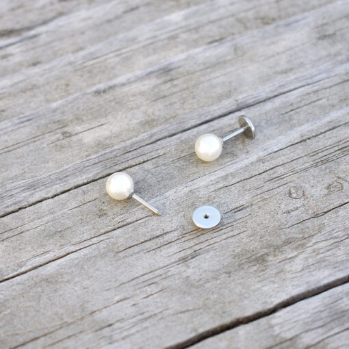 Pearl ComfyEarrings pictured sitting on weathered rustic wood.