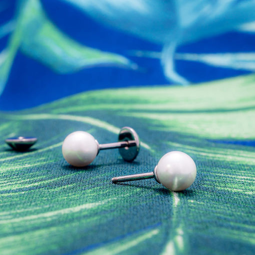 Pearl ComfyEarrings sitting on blue and green tropical print fabric.
