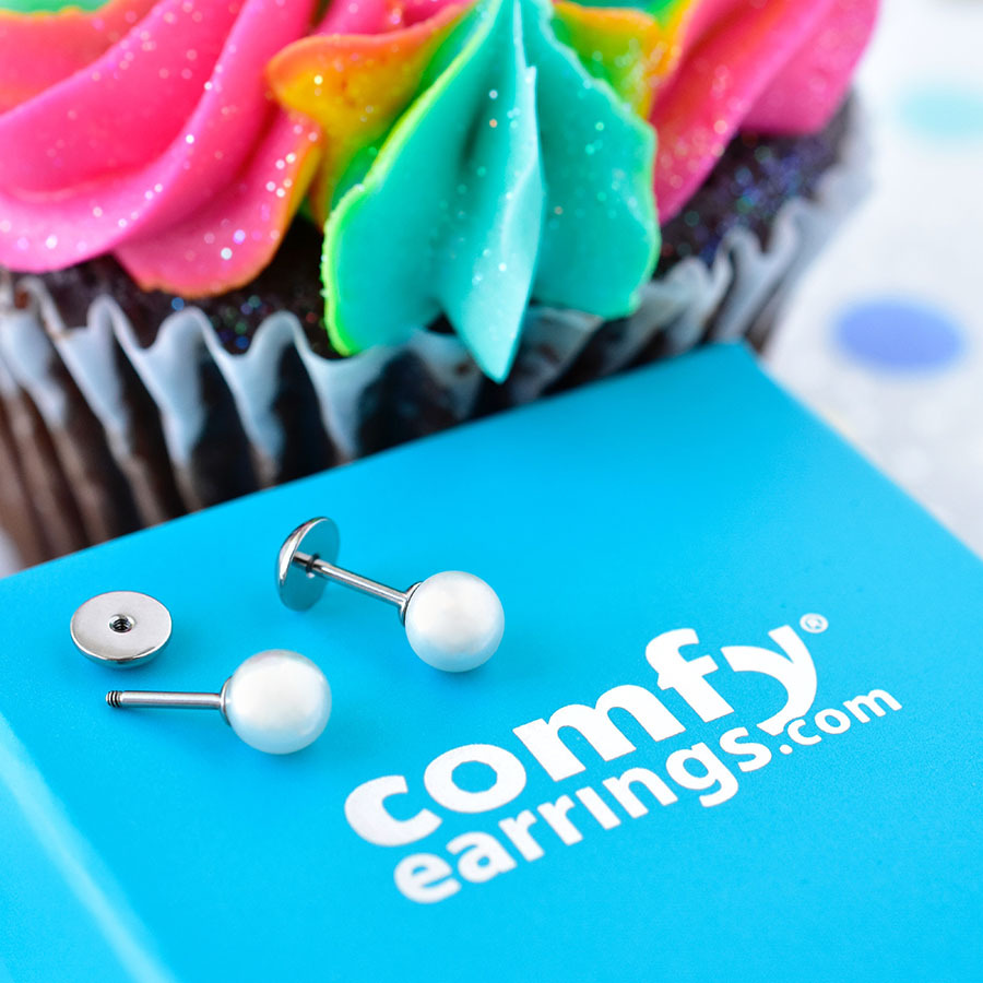 Pearl ComfyEarrings sitting on blue ComfyEarrings box in front of a colorful cupcake