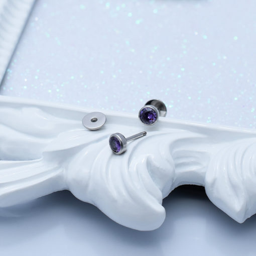 Amethyst ComfyEarrings sitting on the edge of a decorative white picture frame.
