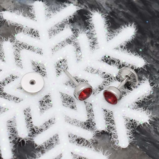 Ruby Red ComfyEarrings sitting on a white icy snow flake ornament.