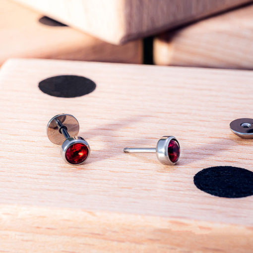 Ruby Red ComfyEarrings sitting on large wooden dice.
