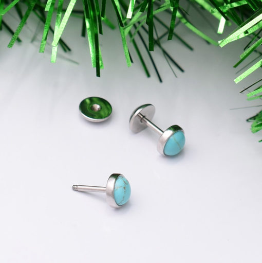 Turqoise ComfyEarrings on white background with green tinsel.