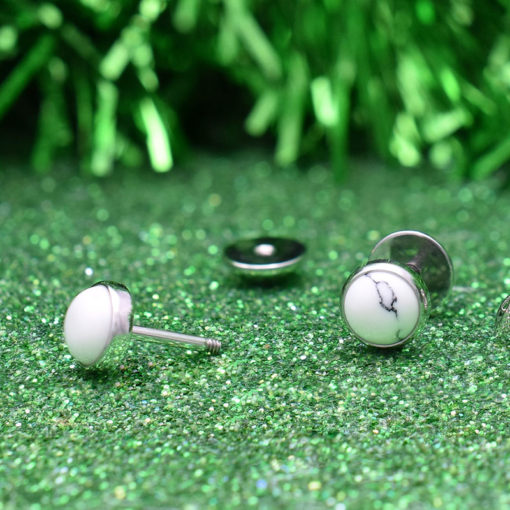 White Marble ComfyEarrings in front of green tinsel on green glitter background.