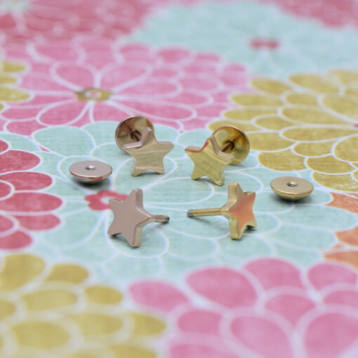 Gold and Rose Gold Star ComfyEarrings pictured on a pink, blue, and yellow floral paper.