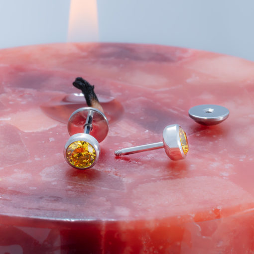 Citrine ComfyEarrings on lit red and orange candle.