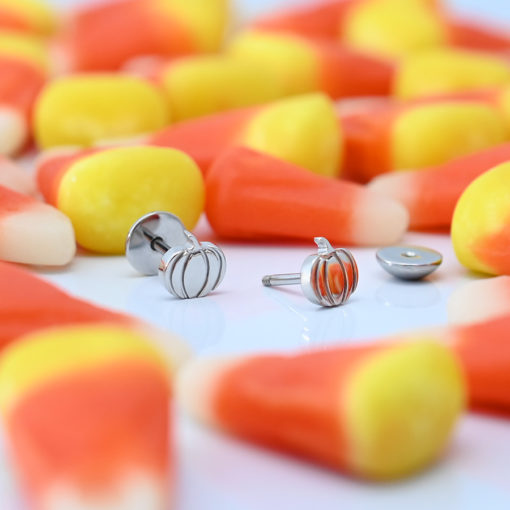 Stainless Pumpkin ComfyEarrings surrounded by candy corn.