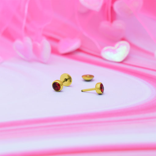 Ruby Red Gold ComfyEarrings on pink swirls with shiny pink hearts in the background.