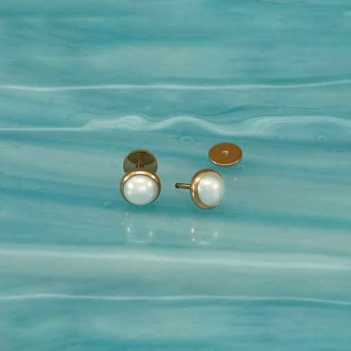 Half Pearl Rose Gold ComfyEarrings sitting on wavy blue grass.
