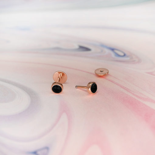 Black Onyx Rose Gold ComfyEarrings sitting on a pink swirl paper