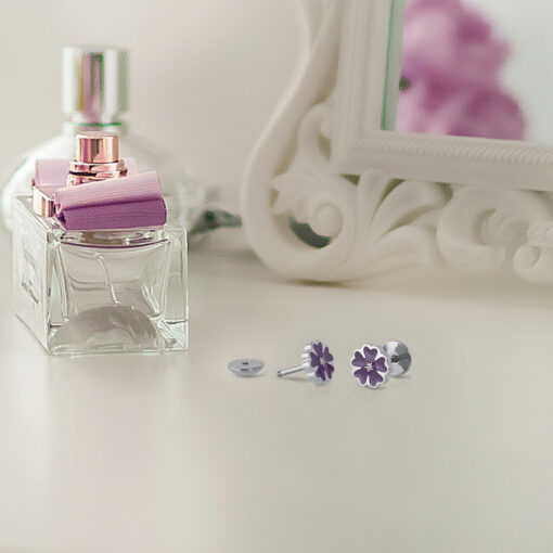 Purple Enamel Flower ComfyEarrings in front of a white mirror and perfume bottles.