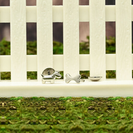 Dog and Bone ComfyEarrings on a mini white picket fence with green moss background.