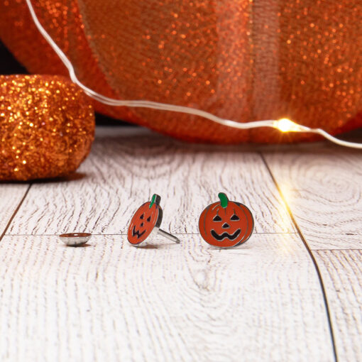 Enamel Jack-o'-Lantern ComfyEarrings in front of sparkly halloween decor.