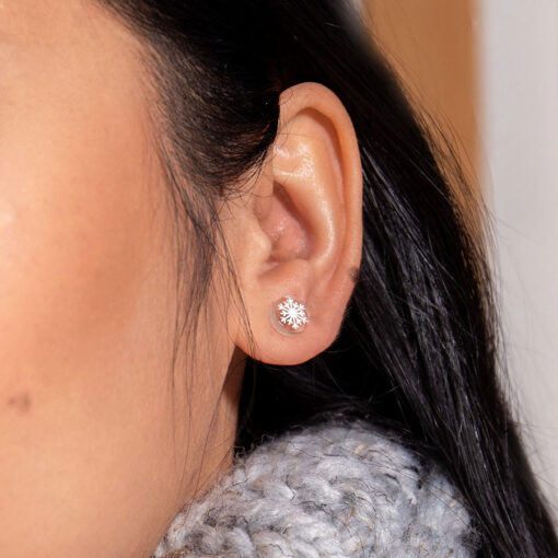 Snowflake ComfyEarrings worn in a model's ear up close.