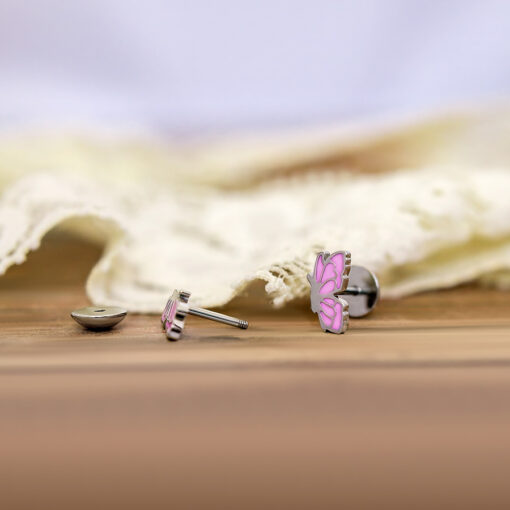 Pink Enamel Butterfly ComfyEarrings on a wood board in front of ivory lace.