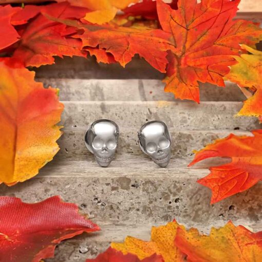 Skull ComfyEarrings on a stone surrounded by orange fall leaves.