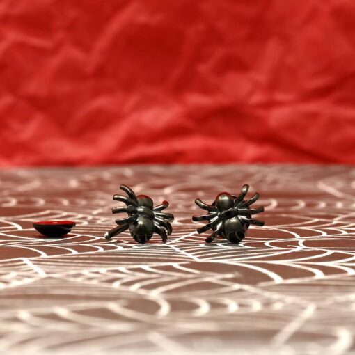 Spider ComfyEarrings black plated pictured on red background.