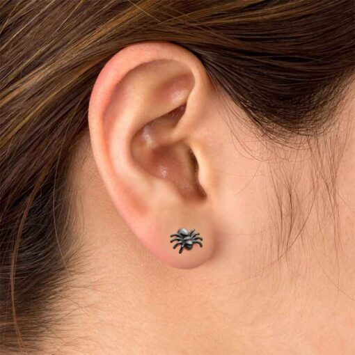 Black plated spider ComfyEarrings shown in a woman's ear.